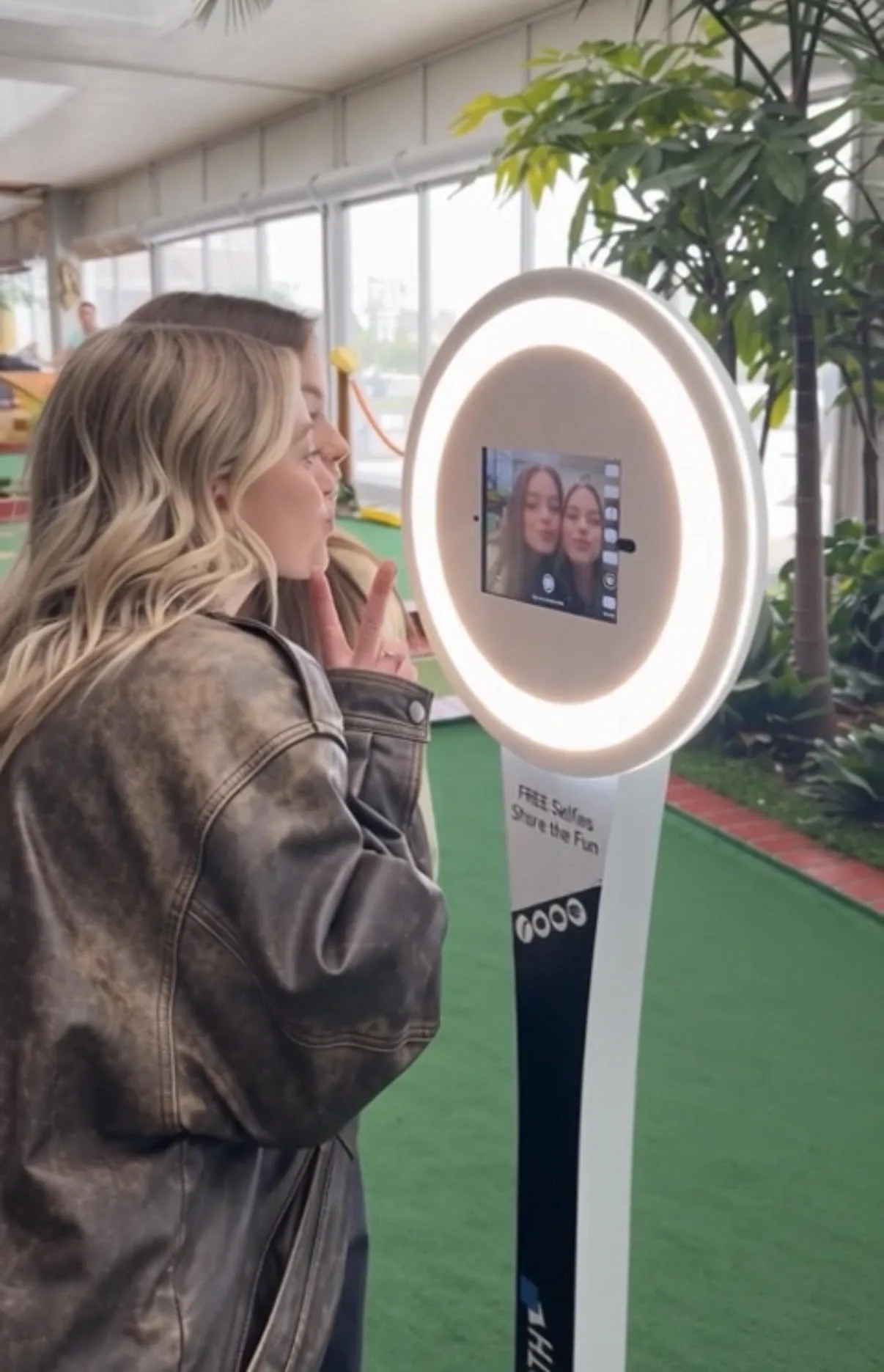 Guests using a BuzzyBooth photo booth at a mini golf center