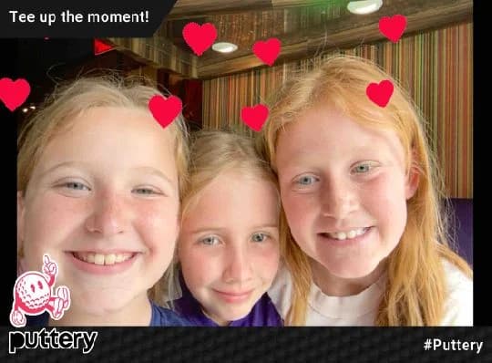 Three young guests smiling in a Puttery BuzzyBooth photo with heart effects