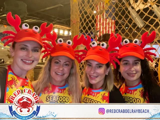 Four Red Crab guests wearing crab hats in a branded photo